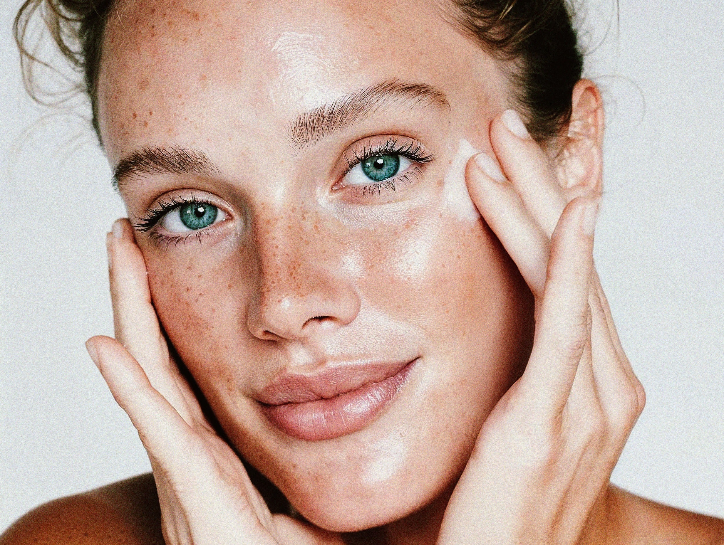 Woman with glowing, healthy skin touching her face — Blanchard Skincare pharmacist-formulated skincare